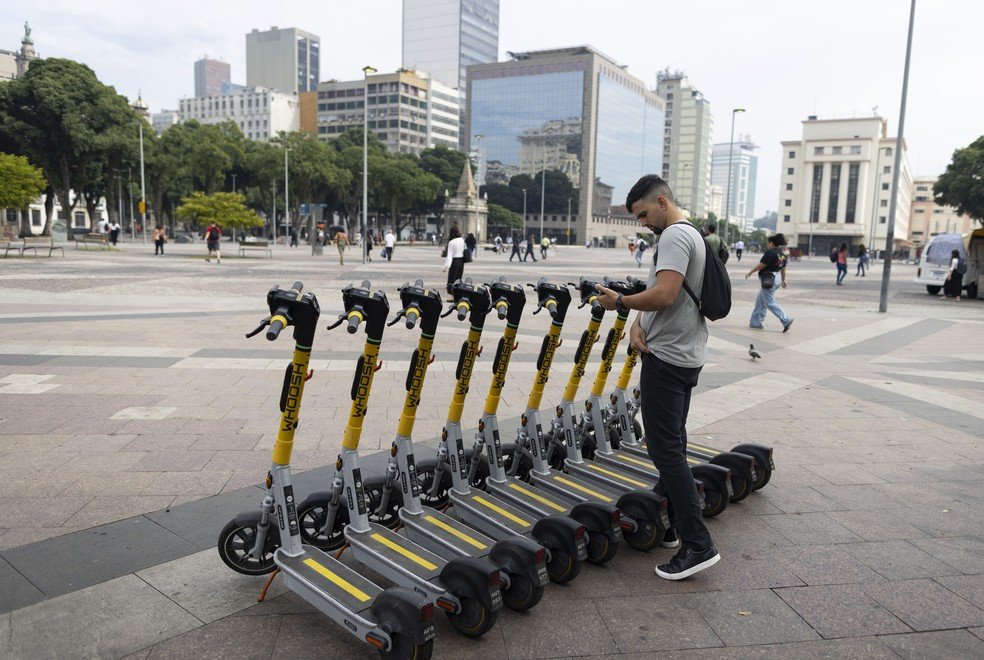 Mateus Porto usa o patinete após descer da barca, na Praça Quinze — Foto: Márcia Foletto / Agência O Globo